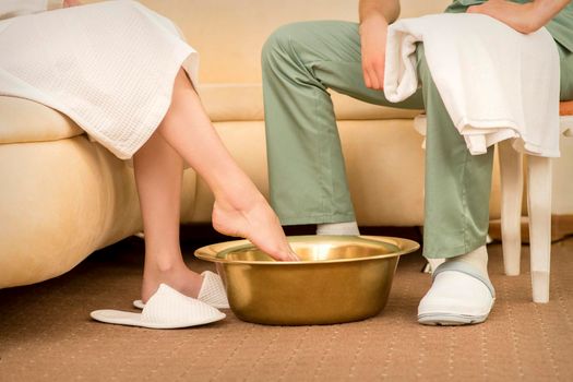 A woman is dipping feet in a bowl before washing feet therapy