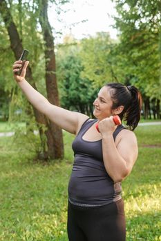 A charming brunette woman plus-size body positive practices sports in nature.