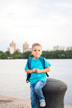 A boy in a blue T-shirt with a backpack on his back. Journey.  The face expresses natural joyful emotions. Not staged photos from nature.