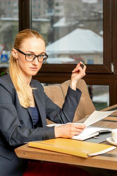 Beautiful young caucasian businesswoman working with documents in a cafe