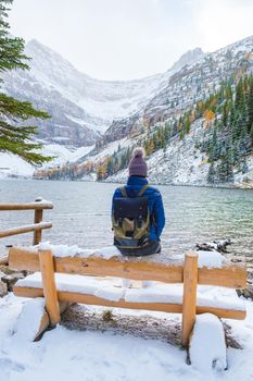 Lake Agnes by Lake Louise Banff national park is a lake in the Canadian Rocky Mountains. A young couple of women sitting on a bench by the lake during a cold day in Autumn in Canada
