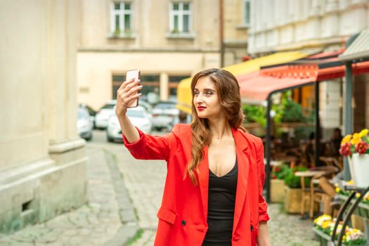 Beautiful young caucasian tourist woman takes a selfie in a European city