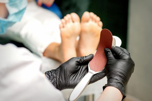 The pedicurist put on a new heel file on the metal handle before the procedure of cleaning the feet in a nail salon