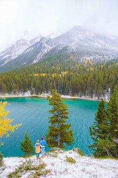 Minnewanka lake in the Canadian Rockies in Banff Alberta Canada with turquoise water, Lake Two Jack in the Rocky Mountains of Canada. a couple of men and women hiking by the lake during snow weather