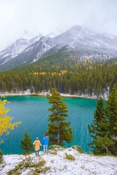 Minnewanka lake in the Canadian Rockies in Banff Alberta Canada with turquoise water, Lake Two Jack in the Rocky Mountains of Canada. a couple of men and women hiking by the lake during snow weather