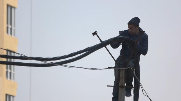 Kyiv,Ukraine - 24.04.2019: Construction worker installing wires in a new building. Technician men fixing or repairing broken power.