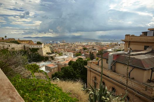 Aerial view of the historical center of Cagliari with clearly visible the various historical buildings of which it is composed with its characteristic architecture under a cloudy sky with an incoming storm.