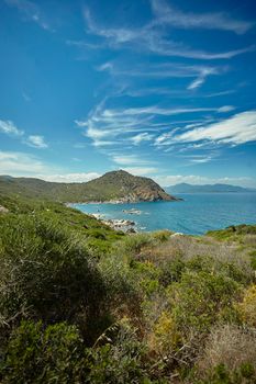 Vertical shot of the panorama of a natural bay in the south of Sardinia in Italy with the mountains overlooking the sea in broad daylight during the summer.