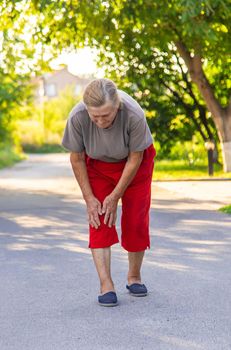 grandmother hurts her knee on the road. Selective focus. People.