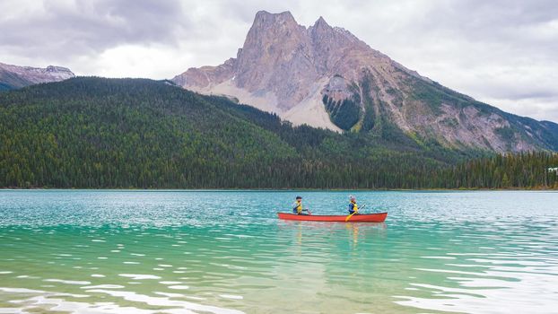 Emerald Lake in Autumn at the Yoho National Park Alberta Canada, men by the Emerald lake Canada. Couple of men and women in a canoe at the lake during a vacation in Canada