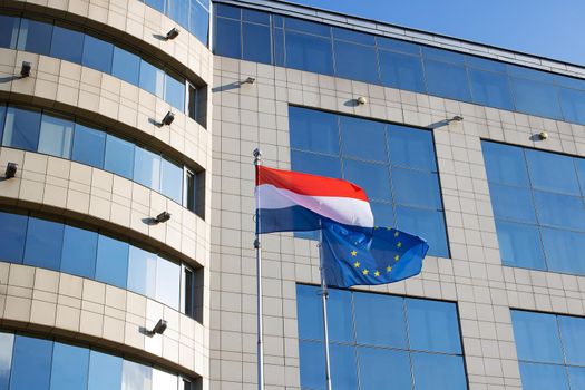 Flags of the EU and the Netherlands at the office building close up
