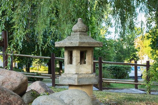 Stone Japanese lantern in a green park close up