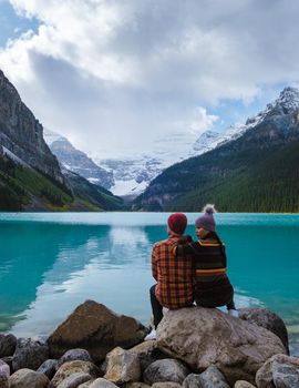 Lake Louise Banff national park, is a lake in the Canadian Rocky Mountains. A young couple of men and women standing by the lake during a cold day in Autumn in Canada