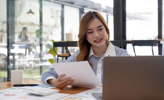 Asian businesswomen sit at their desks and calculate financial graphs showing results about their investments, plan a successful business growth process in the office..