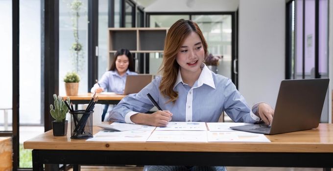 Young beautiful woman using her laptop while sitting in a chair at her working place, Small business owner people employee freelance online sme marketing e-commerce telemarketing concept..