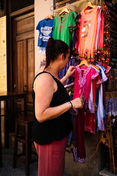 A young woman looking at clothes at street market. Stock photography.