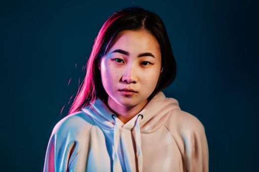 Close up portrait of millennial pretty korean woman with long hairstyle with neon light. Hipster teenager in studio.