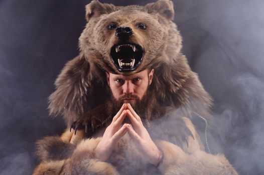 A traditional medieval bearded man dressed as an animal-bear, a symbol of power, strength and greatness. studio shot cosplay.