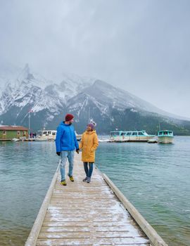 Minnewanka lake in the Canadian Rockies in Banff Alberta Canada with turquoise water, Lake Two Jack in the Rocky Mountains of Canada. a couple of men and women hiking by the lake during snow weather