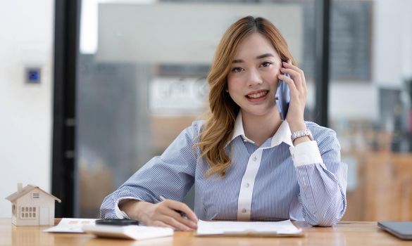 Asian business woman have the joy of talking on the phone, laptop and tablet on the office desk..