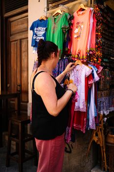 Lifestyle shopping concept, young happy caucasian woman choosing clothes in store on shopping street at daytime. stock photography