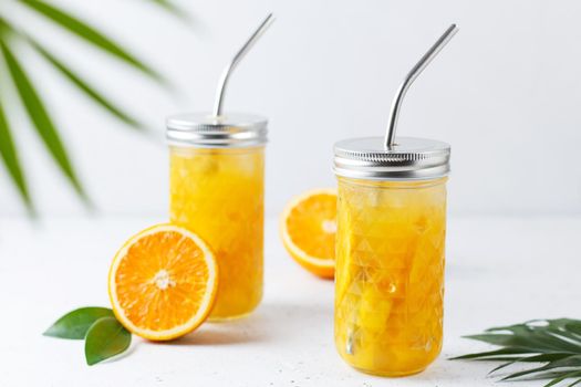 Glasses with orange juice, orange slices and mango on a gray background.