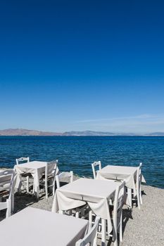 White restaurant tables on the beach in summer - travel, vacation and summer concept. The perfect lunch with a sea view