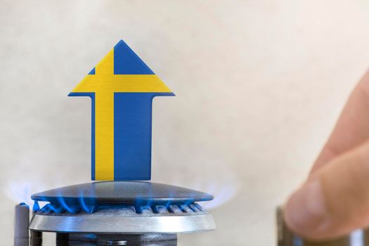 Gas price. Rise in gas prices in Sweden. A burner with a flame and an arrow up, painted in the colors of the Sweden flag. The concept of rising gas or energy prices