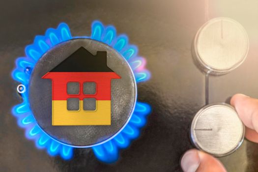 Heating season or gas use in Germany. Concept, model of a house stands near the flame of a gas boiler on a black background. The cost of using natural gas in Germany
