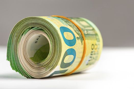 Roll of money. Roll of 100 euro banknotes. Euro banknotes rolled up on a gray background. The concept of financial assistance, real estate purchase, loan or insurance payment