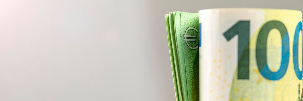 Roll of money. Roll of 100 euro banknotes. Euro banknotes rolled up on a gray background. The concept of financial assistance, real estate purchase, loan or insurance payment