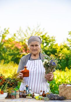 Grandmother makes tinctures from medicinal herbs. Selective focus. People.