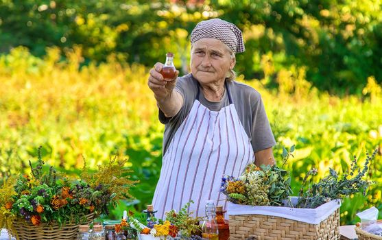 Grandmother makes tinctures from medicinal herbs. Selective focus. People.