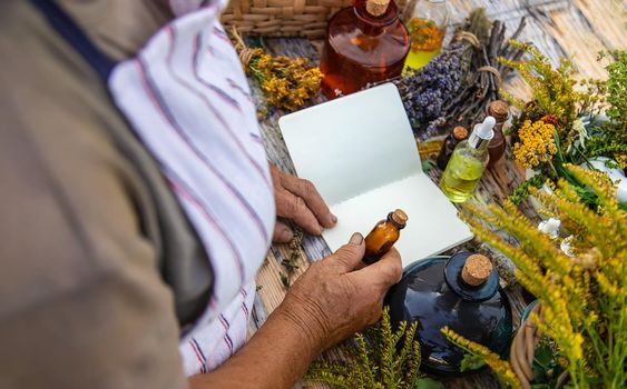 Grandmother makes tinctures from medicinal herbs. Selective focus. People.