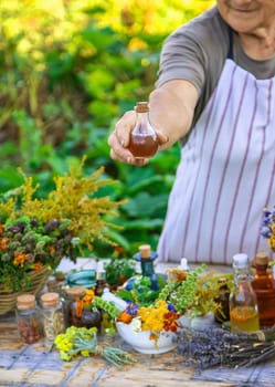 Grandmother makes tinctures from medicinal herbs. Selective focus. People.