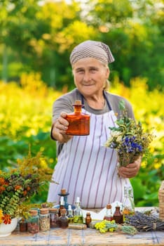 Grandmother makes tinctures from medicinal herbs. Selective focus. People.