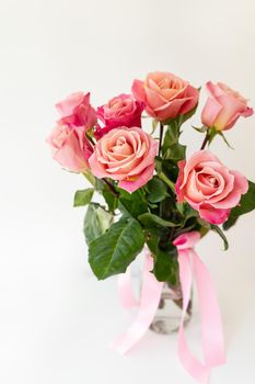 Beautiful bright pink-red roses, flowers in a vase, side view, vertical photo. Flowers for the holiday