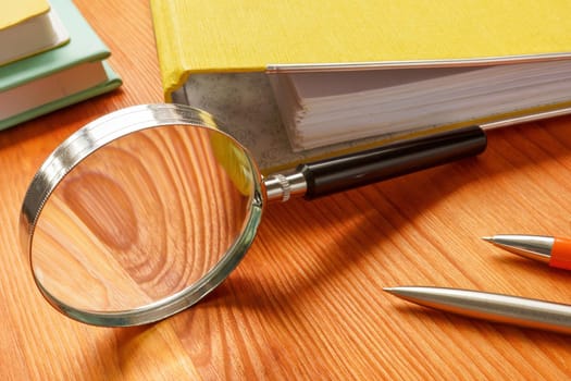 An Office table with folder and magnifying glass. HR investigation concept.