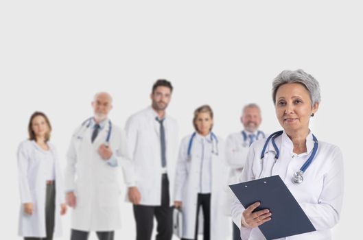 Team of doctors and asian mature female leader woman with document folder in front on gray background