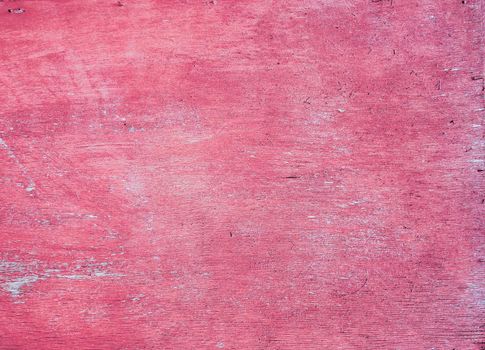 Plywood surface with worn, time-damaged red paint. Fuchsia color decorative background.