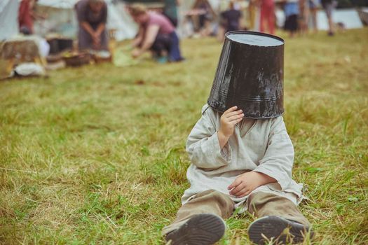 The boy fooling around puts a bucket on his head at viking festival