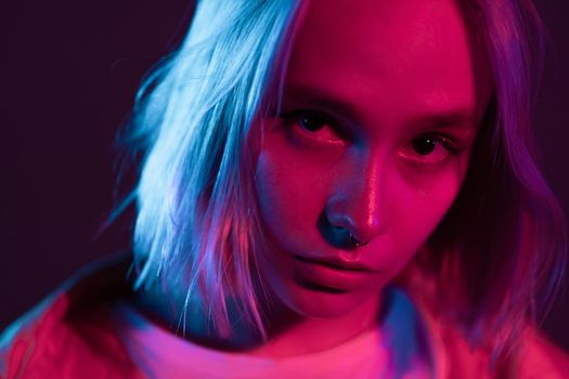 Portrait of unusual beautiful glamour and fashion girl with colorful hairstyle on studio background. Young woman in pink and violet neon light