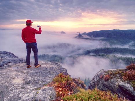 Male traveler using mobile cell phone sharing fall mountains landscape view for friend through scial network. 