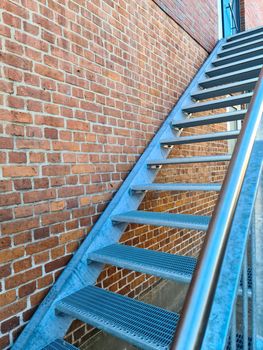 Close up view on metallic stairs in front of a brick wall