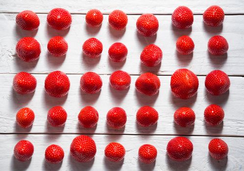 abstract pattern of red fresh strawberries laid out on a white board background . High quality photo