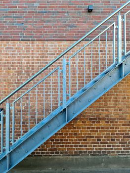 Close up view on metallic stairs in front of a brick wall