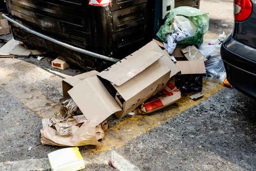 A Garbage dumped on the street next to a street waste container.