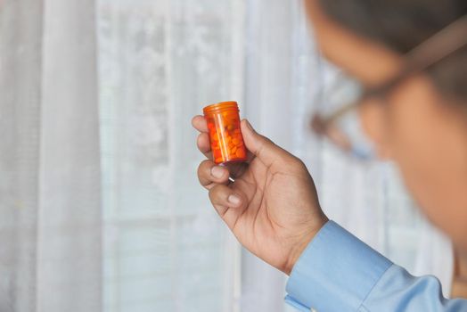 rear view of man holding pill container on blue background .