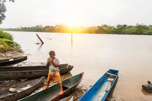 Indigenous boy standing on wooden barges known as cayuco in the northern caribbean of Nicaragua