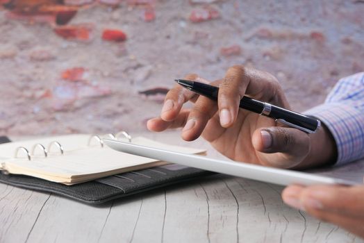 man's hand working on digital tablet at office desk